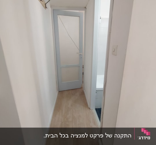 מסדרון דירה עם התקנת פרקט בגוון עץ בהיר ופאנלים לבנים